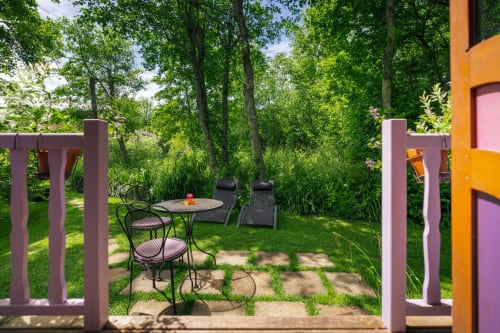 Coin salon du jardin des Gîtes du Rouard à Camiers avec chaises longues, table de repas et arbres environnants