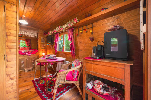 Chambre colorée Roulotte LA VERDINE aux Gîtes du Rouard à Camiers avec intérieur en bois, accents roses et vue sur le jardin