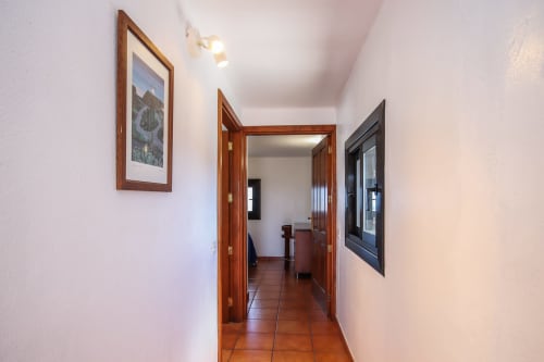 Luminoso pasillo con puertas de madera y suelo de azulejos en Apartamento Superior de Villanueva Lanzarote, Mala, España