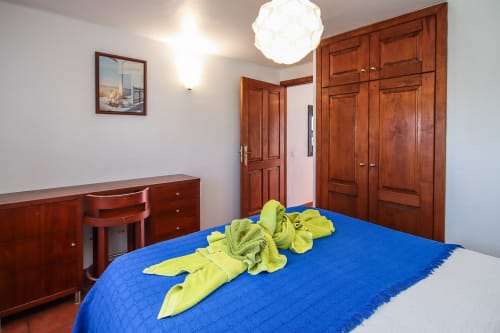 Dormitorio luminoso en apartamento de Lanzarote con colcha azul, muebles de madera y decoraciones de arte textil