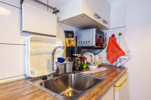 Pequeña cocina en apartamento de Villanueva Lanzarote con fregadero de acero inoxidable, cafetera y muebles blancos