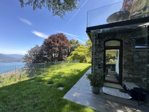 Stone luxury spa retreat terrace overlooking Lake Maggiore, Stresa, with manicured lawn and mountain views