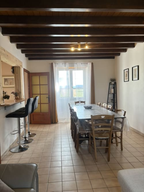 Salle à manger moderne avec poutres en bois, table de repas, coin cuisine et vue sur les montagnes au Mas De Bannayoux, Couteuges