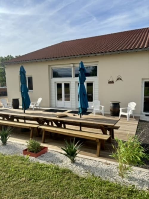 Salle de réception Mas De Bannayoux avec terrasse en bois, parasols bleus, chaises blanches et bâtisse en pierre de style provençal