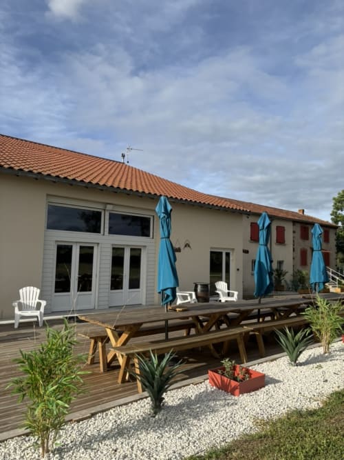 Salle de réception du Mas De Bannayoux avec terrasse en bois, parasols bleus et vue sur les montagnes à Couteuges