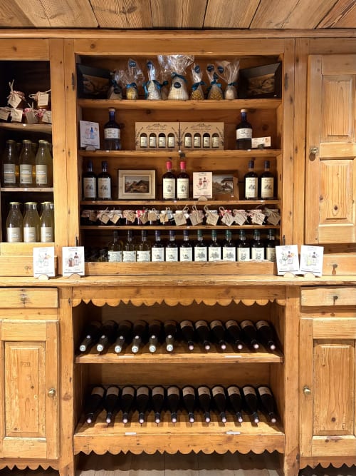 Meuble à vin en bois à La Ferme 1828 B&B à Demi-Quartier, présentant bouteilles de vin, spiritueux et produits locaux