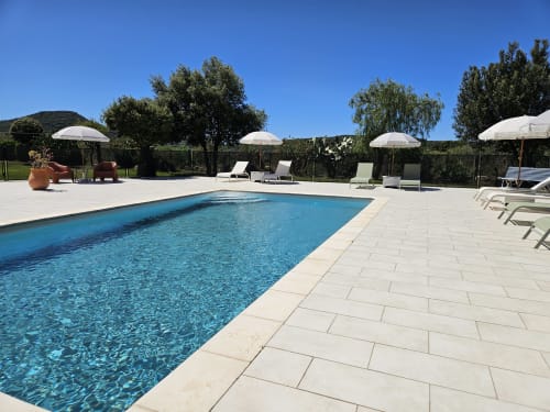 Hotel Les Mouettes pool in Belgodère with sunbeds, umbrellas, and lounging area under clear blue sky