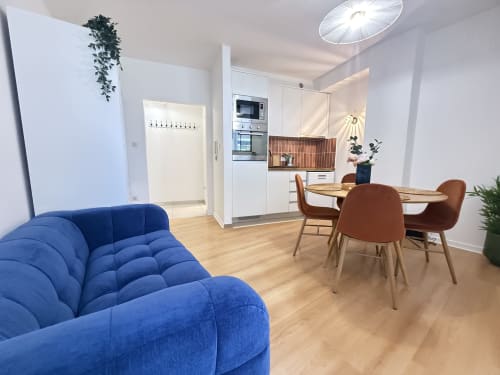 Appartement moderne à Luxembourg Limpertberg avec canapé bleu, table à manger en bois, cuisine blanche et vue sur la ville