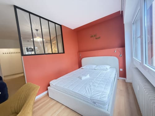 Chambre moderne Mattbnb à Luxembourg Limpertberg avec mur corail, lit blanc, paroi vitrée et vue sur la ville