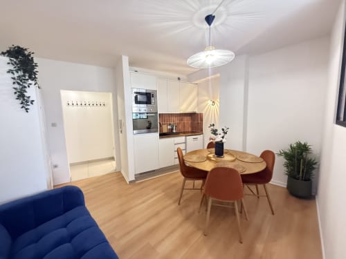 Salle à manger moderne à Luxembourg Limpertberg avec table en bois, chaises rouges, cuisine blanche et canapé bleu