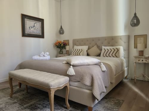 Chambre élégante à La Maison du Clocher à Saint-Emilion avec lit en velours beige, banc, luminaires suspendus et décoration classique