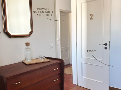 Room 2 at Casa Idalia Comporta with wooden dresser, mirror, and doors leading to private bathroom and balcony in Comporta,