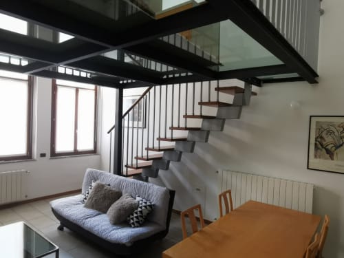 Moderna zona living con soppalco alle scale, divano futon e vista sulla città al The Kraken Inn di Bergamo