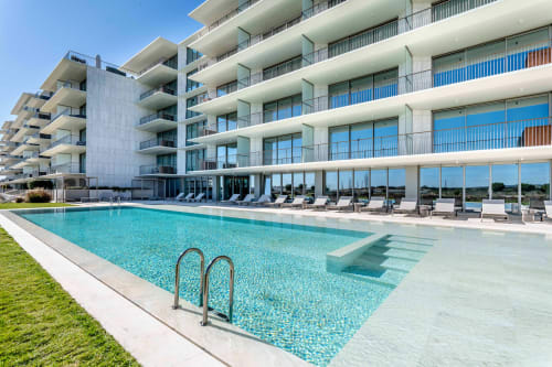 Moderno hotel AlgarStays em Silves com piscina turquesa, espreguiçadeiras e edifício branco de vários andares sob céu azul