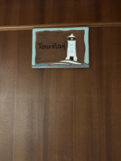 Cartel de la habitación Touriñán con ilustración de faro en Hotel O Esqueiro, Malpica