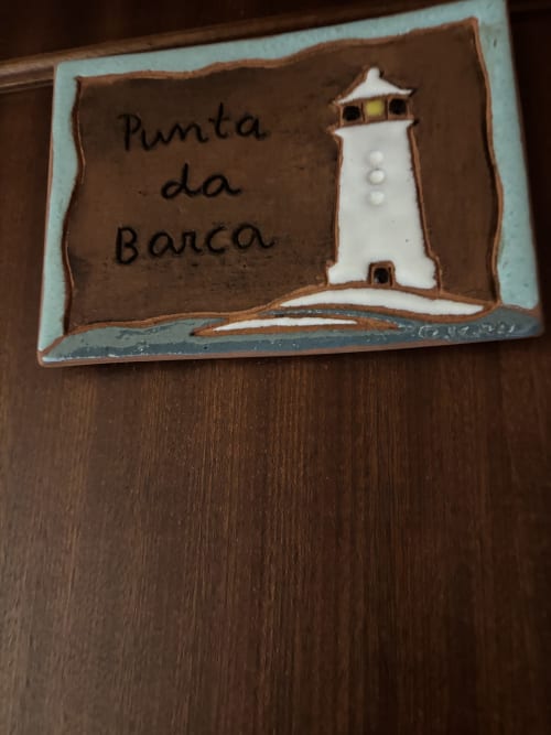 Placa cerámica con inscripción 'Punta da Barca' y diseño de faro en Hotel Restaurante O Esqueiro, Malpica, A Coruña