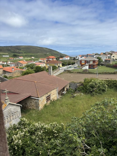 Garden view from Hotel O Esqueiro room in Malpica, A Coruña, overlooking village buildings and green hillside