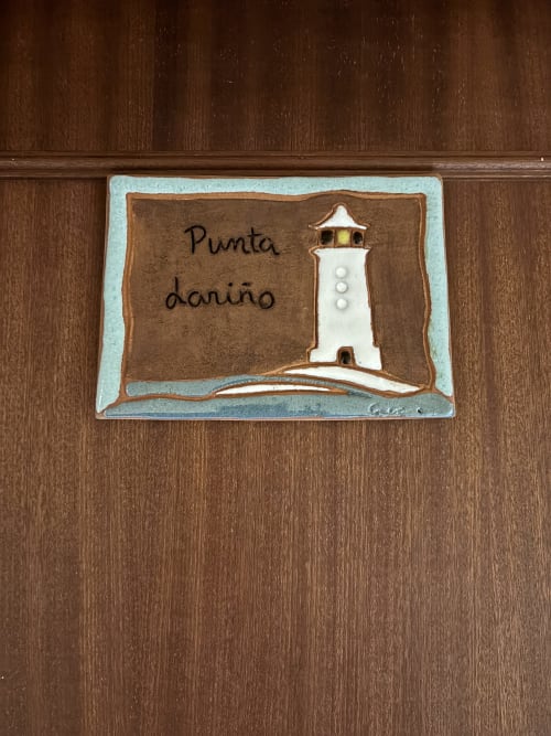 Placa de cerámica con la inscripción 'Punta dariño' e ilustración de faro en Hotel Restaurante O Esqueiro, Malpica
