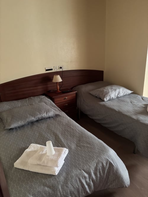Twin beds with gray bedding and white towels at Hotel Restaurante O Esqueiro in Malpica, A Coruña