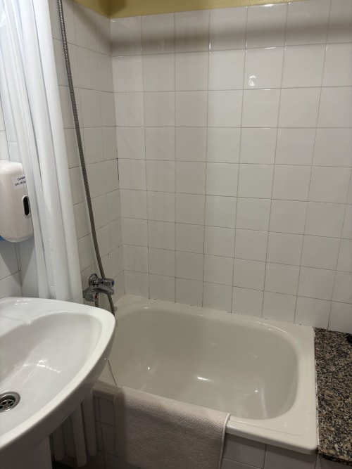 Clean bathroom with white tile walls and bathtub at Hotel Restaurante O Esqueiro, Malpica