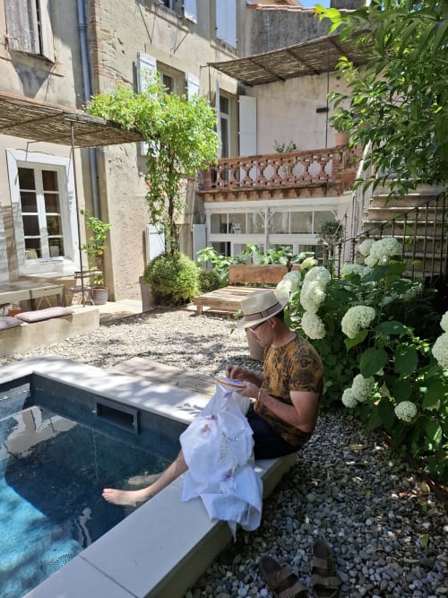 Un client profitant de la piscine à la cour de Camellas Lloret B&B à Montréal, avec hortensias blancs et patio en pierre