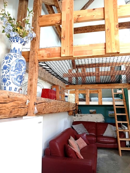 Chambre rustique du gîte de Chaparon avec poutres en bois, canapé rouge, mezzanine et vase bleu en céramique à Lathuile