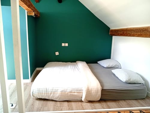 Chambre cosy au gîte de Chaparon à Lathuile avec mur d'accent bleu-vert, poutres en bois et deux lits aux oreillers rayés