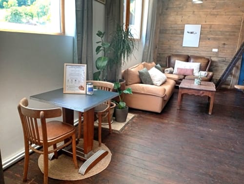 Espace lounge du refuge de Chaparon avec mobilier en bois, fauteuil beige et vue sur les montagnes à Lathuile
