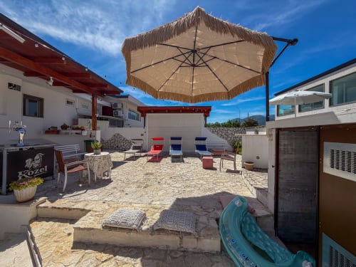 Strandnaher Patio von Stella CasaBono mit Strohdach-Sonnenschirm, Liegestühlen und Sand in Sulmona
