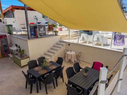 Terrasse des Hotels Stella CasaBono in Sulmona mit gelbem Sonnenschirm, schwarzen Esstischen und cremefarbenen Stufen