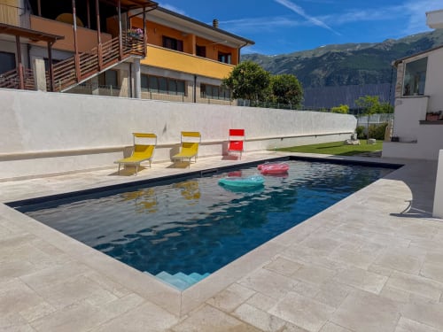 Pool des Hotels Stella CasaBono in Sulmona mit Liegestühlen, aufblasbaren Flössen und Bergblick