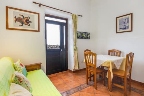 Acogedora sala de estar con mesa de comedor, sillas de madera, sofá verde y puerta hacia terraza con vistas al jardín en Villanueva