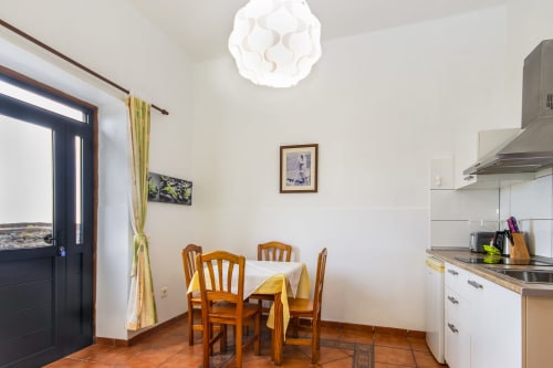 Cocina y comedor en Apartamento Deluxe de Villanueva Lanzarote, Mala con sillas de madera, muebles blancos y