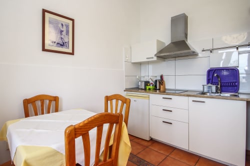 Cocina y comedor luminosos en Apartamento Deluxe de Villanueva Lanzarote con sillas de madera, muebles blancos y acero inoxidable