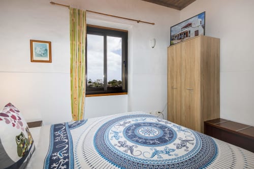 Habitación de suite en Villanueva Lanzarote con ropa de cama estampada azul, armario de madera y vistas al jardín