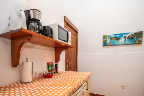 Cocina de apartamento deluxe en Villanueva Lanzarote con encimera de lunares naranjas, estantería de madera y vista costera
