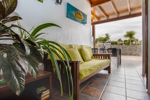 Apartamento de lujo en Villanueva Lanzarote con sofá verde, plantas tropicales y terraza con vistas al jardín en Mala