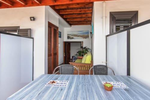 Terraza cubierta con mesa de madera en Villanueva Lanzarote, Mala, con sillas de mimbre y vistas al jardín