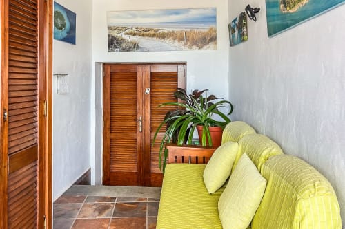 Sofá amarillo verdoso brillante en apartamento de Villanueva Lanzarote con puertas de madera y plantas en macetas