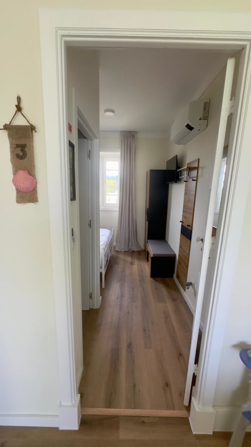 Corredor moderno do Pink-Shell BnB em Santiago de Riba-UI, Portugal, com piso em madeira que leva ao quarto