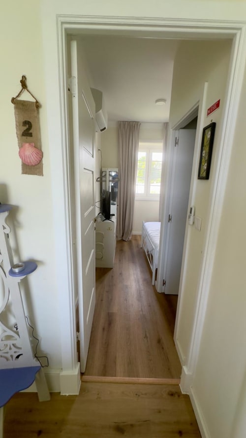 Corredor estreito com piso em madeira na Pink-Shell B&B Santiago de Riba-UI, conectando áreas de quartos de hóspedes com portas brancas