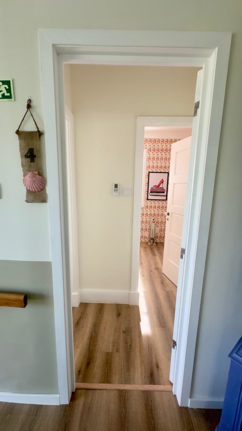 Vista através da porta do Quarto Rainha Superior no Pink-Shell B&B em Santiago de Riba-UI mostrando corredor com piso de madeira