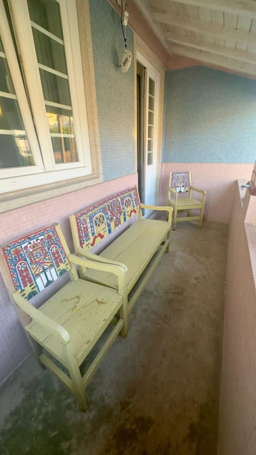 Bancos amarelos com almofadas coloridas na varanda coberta do Pink-Shell BnB em Santiago de Riba-UI, Portugal