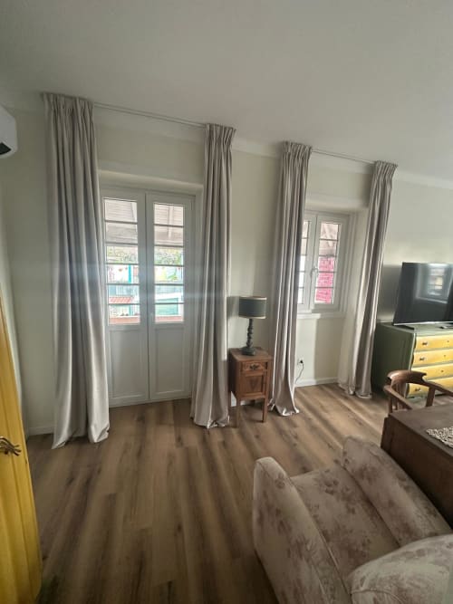 Suíte Familiar com Varanda no Pink-Shell B&B com sala de estar, cortinas cinzas, piso de madeira e portas com vista para o jardim