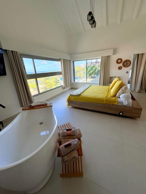Chambre côtière luxueuse à Maly Blue Location au Moule avec literie jaune, baignoire indépendante et vue sur l'océan