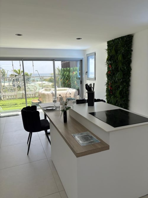 Cuisine moderne à Maly Blue Location avec îlot, mur vert, chaise noire et terrasse vue océan au Moule, Guadeloupe