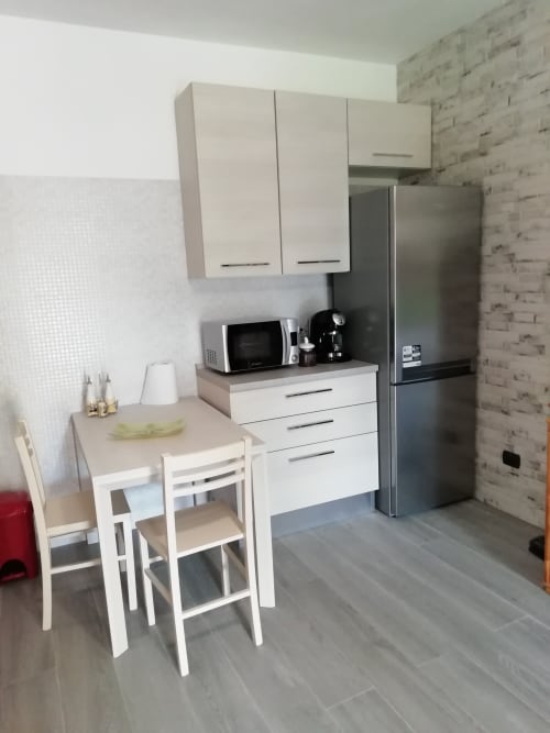 Angolo cottura moderno con pensili bianchi, frigorifero inox, microonde e tavolo nella Villa Acquamarina