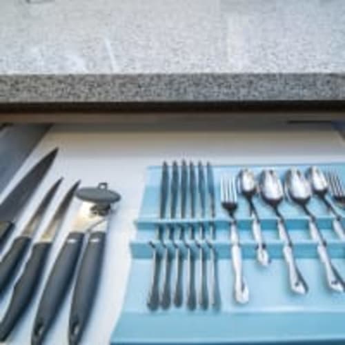 Cubiertos y utensilios organizados en cajón azul del organizador en Apartamentos Posada Country, Guadalajara