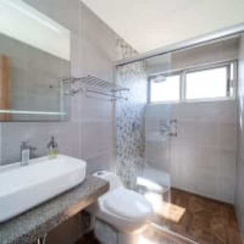 Baño moderno en Apartamentos Posada Country, Guadalajara con ducha amplia, lavabo blanco, inodoro y luz natural