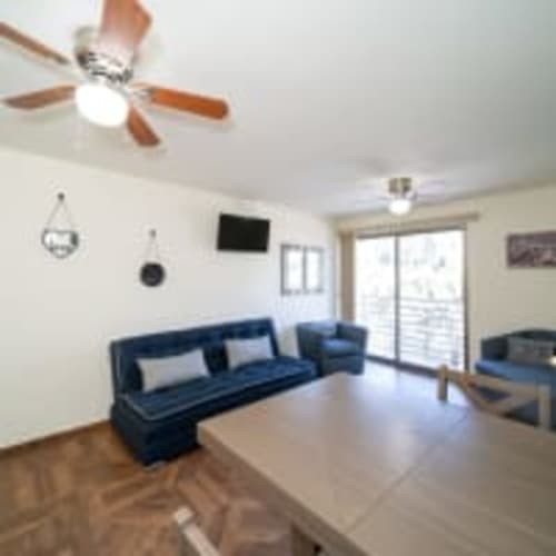 Moderno salón en Apartamentos Posada Country, Guadalajara: sofá azul, ventilador de techo, TV y puertas de vidrio